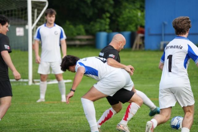 Players battle shoulder to shoulder for the ball in a Germania Football Club summer league game, June 2025