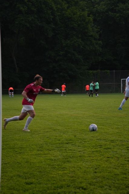 A goalkeeper in red throws the ball out to restart play, June 2025