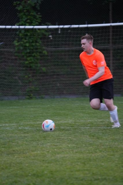 A player in orange chases down a loose ball at Germania, June 2025