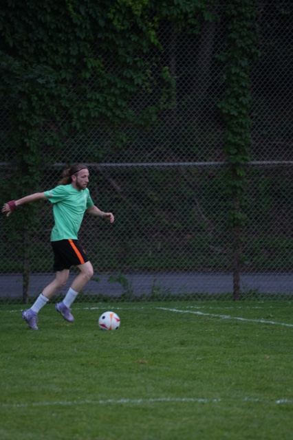 A player in green lines up a pass along the fence at Germania, June 2025
