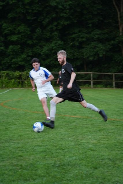 A player in black winds up a strike as a defender in white closes in, June 2025